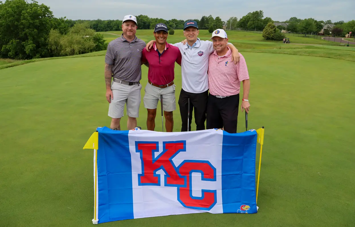 Jayhawk Open Golf Tournament participants behind a KC flag